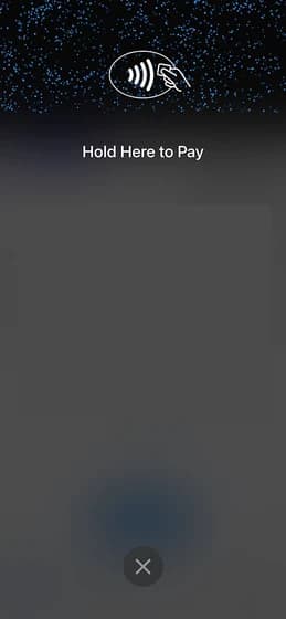 Tap to Pay prompt filling a phone screen: a contactless symbol above the words Hold Here to Pay